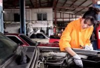 dolly shot: Asian young female car mechanic checking on vehicle engine